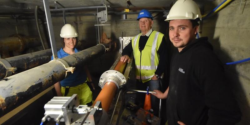 Smilende og fornøyd etter en viktig test av systemene i juni 2017. Operatør Jonas Hansen fra Båsum Boring AS (nærmest) sammen med Borghild T. Folkedal, som den gang representerte Hawle Water Technology og daværende prosjektleder John Bjørningstad, Oslo VAV. Her nede i et av testrommene for tilkobling av stikkledning til hovedvannledningen.